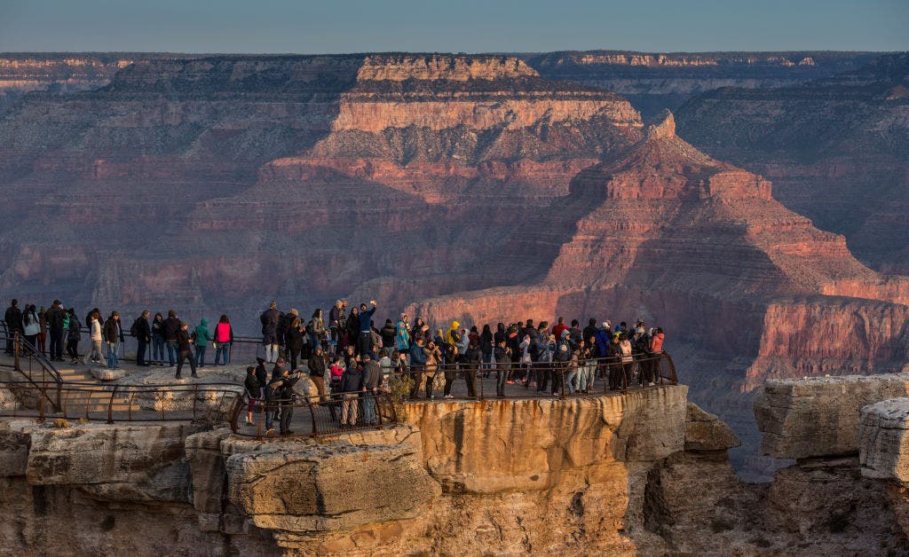 A crowd of tourists gather at Mather Point Lookout, located on the South Rim, to take pictures and watch the sunrise
